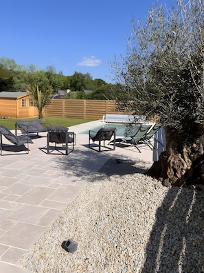 A backyard with a swimming pool, outdoor seating, a wooden fence, and a palm tree. - Terra Cotta Guest Room with Shared Pool, Communal Terrace and Wi-Fi (Lanvollon)