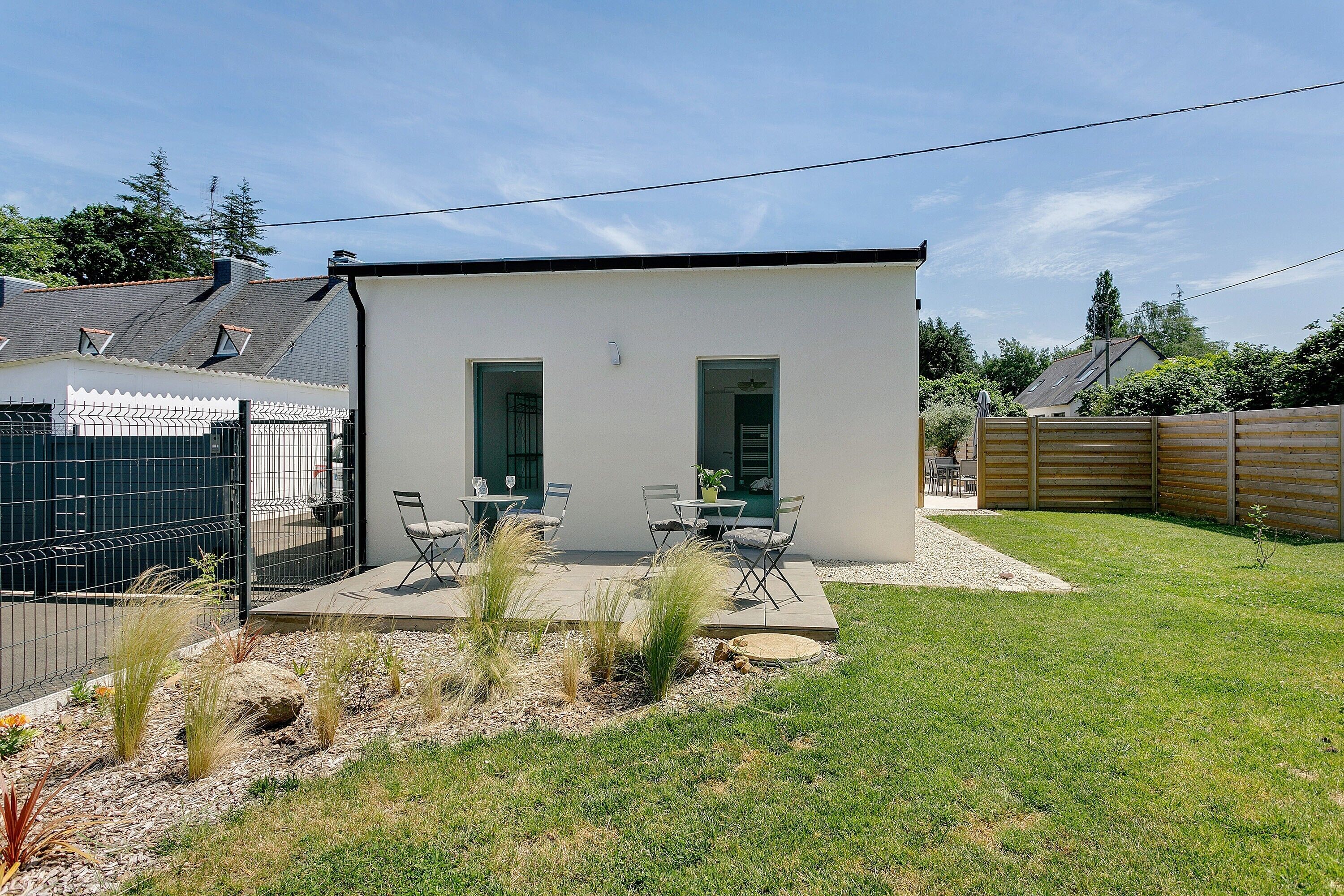 Une maison moderne dotée d’un patio, d’un espace salon extérieur et d’une cour clôturée.