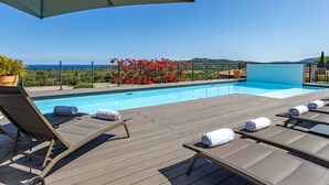 A poolside area with lounge chairs, a pool, and a view of the sea. - Villa Gecko Di Santa Lucia (Zonza)