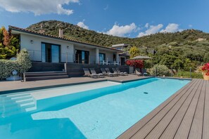 Een moderne villa met een zwembad, terras en uitzicht op de heuvels.