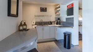 A compact kitchen with white cabinets, a countertop, a sink, and a trash bin. - Villa Gecko Di Santa Lucia (Zonza)