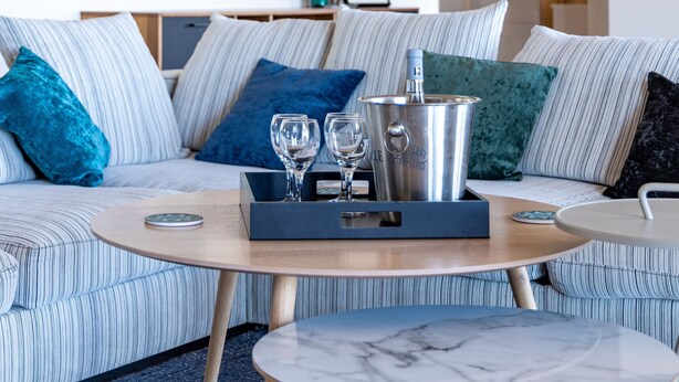 A modern living room with a striped sofa, a coffee table, and a tray with glasses and a thermos. - Villa Gecko Di Santa Lucia (Zonza)