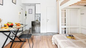 A compact room with a bunk bed, a kitchenette, and a dining area with breakfast.
