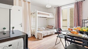 A bunk bed with a breakfast table, a kitchen area, and a large window with curtains.