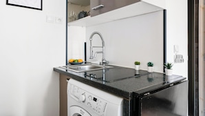A modern kitchen with a built-in dishwasher, a stainless steel sink, and a black countertop.