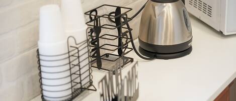 A kitchen counter with a coffee maker, a metal rack with cups, and a sign with the word 'HOME'.