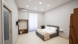 A bedroom with a bed, bedside table, and a window with curtains. - Napoli Incanto (Naples)
