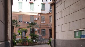 An urban street view with a building featuring balconies, a gate, and potted plants. - Napoli Incanto (Naples)