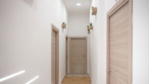 A narrow hallway with wooden doors, a tiled floor, and wall-mounted planters. - Napoli Incanto (Naples)