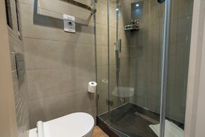 Ein modernes Badezimmer mit einer Duschkabine, einer Toilette und einem Händetrockner.