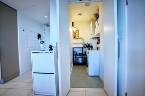 Ein schmaler Flur mit einer Waschmaschine, einem Kühlschrank und einer Küchenzeile mit Spüle und Herd.