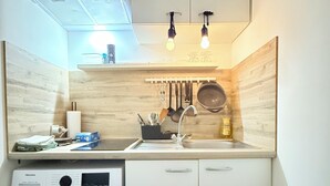 A compact kitchen with a washing machine, a sink, and hanging utensils. - 2 bedrooms - baby crib & furnished  (Luxembourg City)