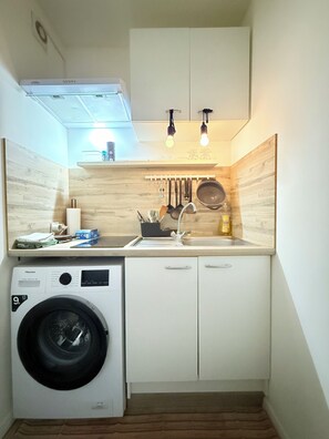 A compact kitchen with a washing machine, a sink, and hanging utensils. - 2 bedrooms - baby crib & furnished  (Luxembourg City)