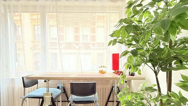 A dining area with a table, chairs, a potted plant, and a view of buildings through the window. - 2 bedrooms - baby crib & furnished  (Luxembourg City)