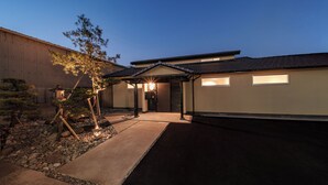 A modern building with a covered entrance, a stone pathway, and a small tree. - Furugo BASE (Oita)
