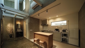 A modern kitchen with a central island, built-in appliances, and a large window. - Furugo BASE (Oita)