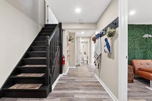 Ein modernes Interieur mit einer Treppe, einer grünen Wand und einem braunen Ledersofa.