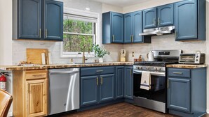 A kitchen with dark blue cabinets, stainless steel appliances, a window, and a wooden countertop. - 6BR + Hot Tub + Firepit + Playroom | Mins to Hunter Mountain + Catskills Hikes (Tannersville)