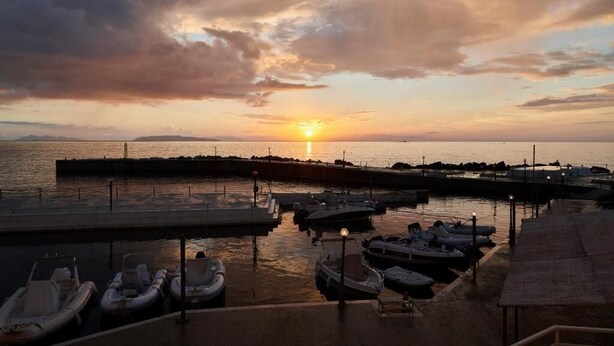 A marina with boats docked, a pier, and a sunset over the water. - Hotel Tirreno (Pizzolungo)