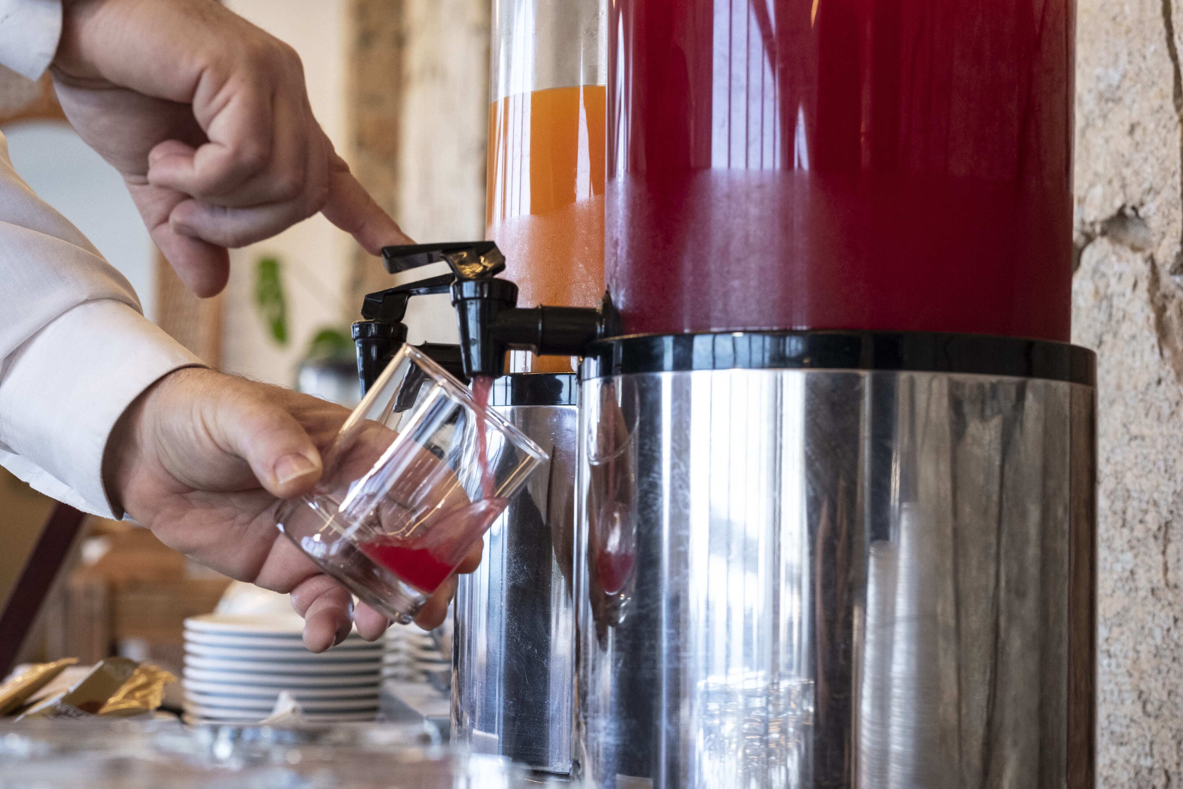 Una persona operando un dispensador de bebidas, mientras se llena un vaso.