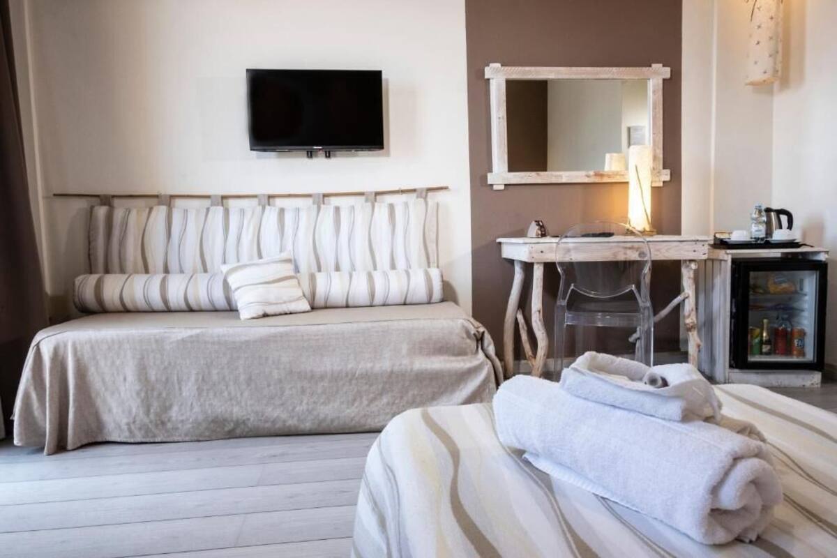 Habitació d'hotel amb llit, televisió, mirall, escriptori i minibar.