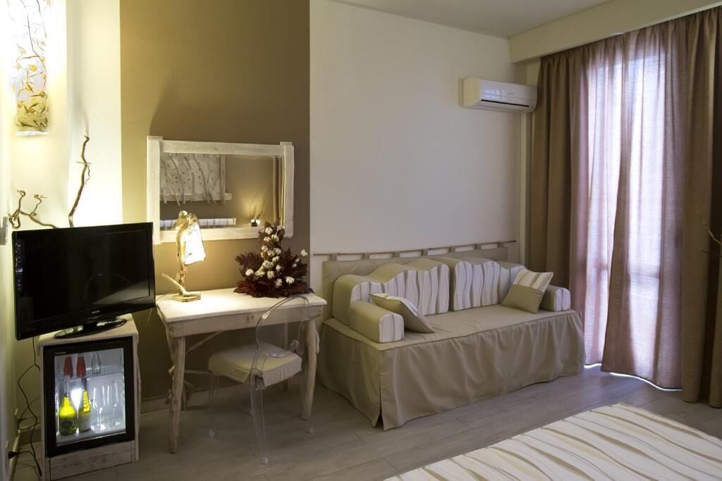 Habitació d'hotel amb un llit, escriptori amb cadira, televisió i aire condicionat.