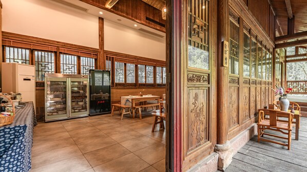 Un interior de madera tradicional con zona de comedor, refrigerador y un ventanal con diseños intrincados.