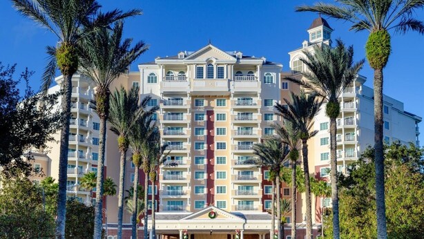 A multi-story hotel with a central entrance, balconies, and palm trees. - Family 3BR Retreat – Water Park, Pools & Disney Access (Kissimmee)