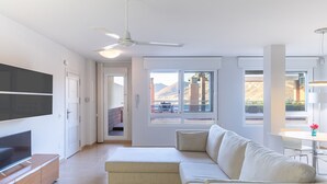 En moderne stue med et fladskærms-tv, en sofa og et spiseområde med et bord og stole.
