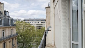 Een gebouw met balkon, boom en straatbeeld.