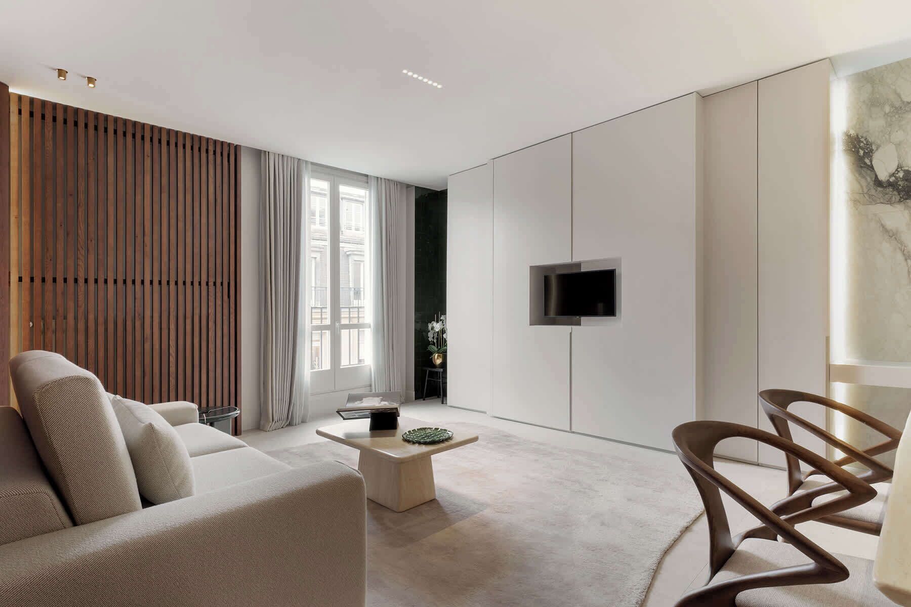 A modern living room with a sofa, coffee table, and a TV mounted on the wall.