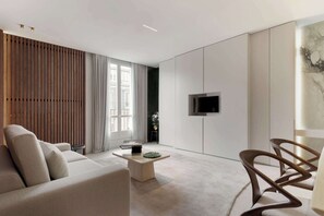 A modern living room with a sofa, coffee table, and a TV mounted on the wall. - A Splendid 2-BR/2Ba w/ Services - Champs Elysées (Paris)