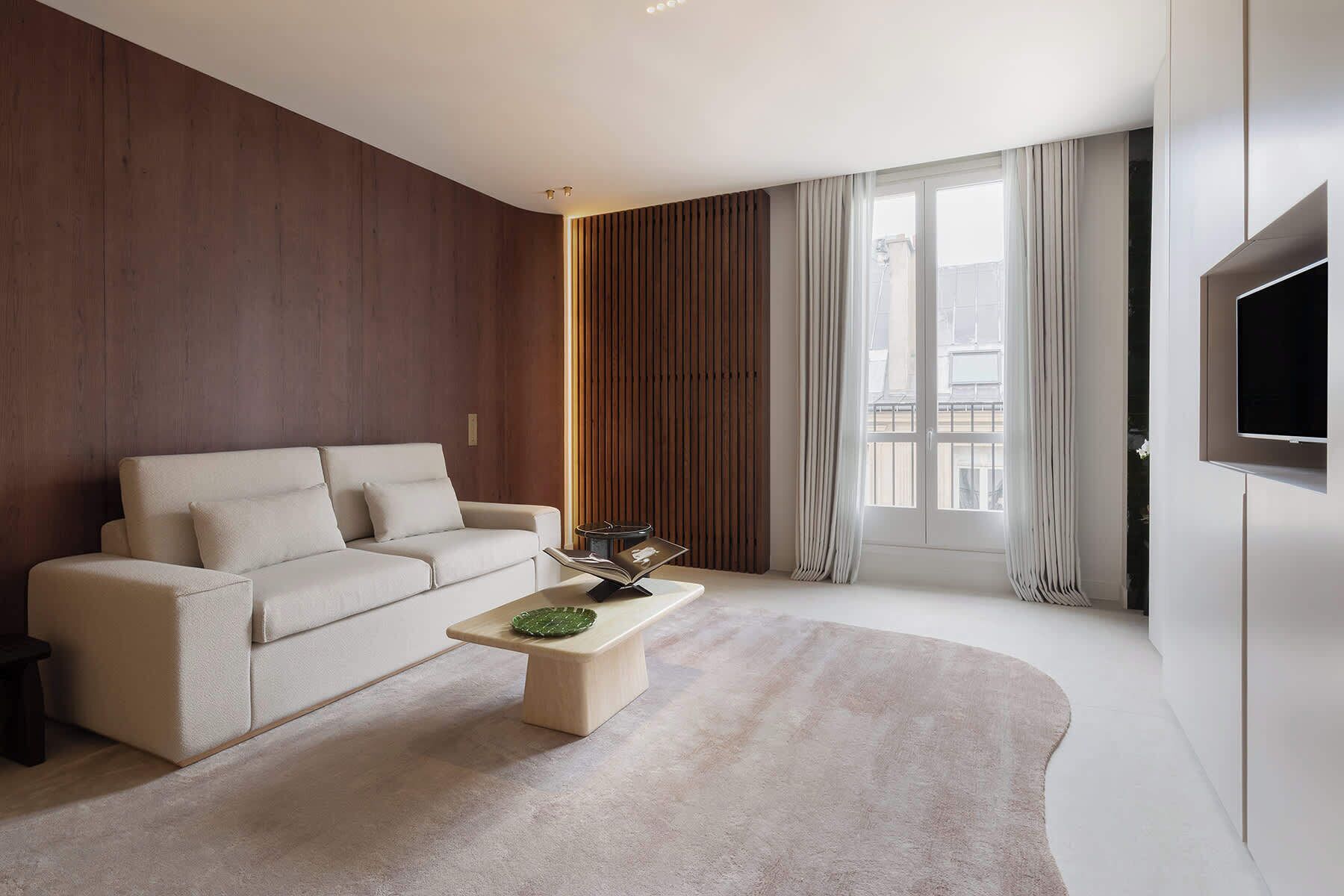 A modern living room with a sofa, coffee table, and a TV mounted on the wall.