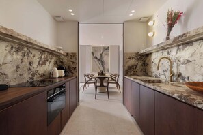 A modern kitchen with marble countertops, a built-in oven, and a dining area with a table and chairs. - A Splendid 2-BR/2Ba w/ Services - Champs Elysées (Paris)