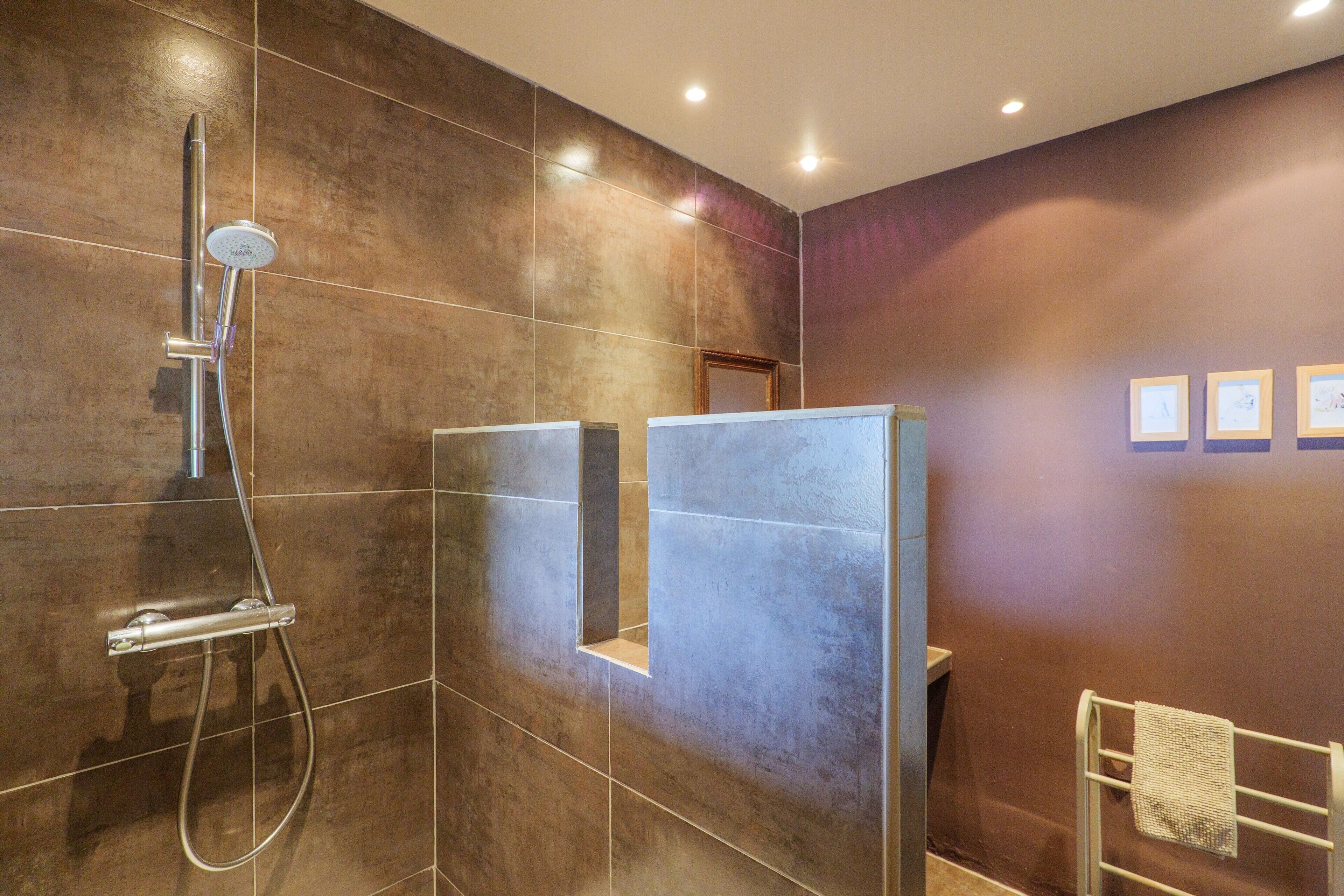 Une salle de bain moderne avec une douche, un porte-serviettes et un tableau encadré au mur.