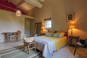A bedroom with a bed, bedside tables, a desk, a chair, and a window.