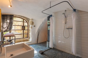 Une salle de bain avec une baignoire, une douche et une fenêtre avec des rideaux.