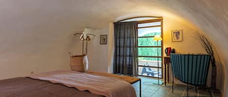 Une chambre à coucher avec un lit, une chaise, une lampe, une fenêtre et une vue sur l’extérieur.