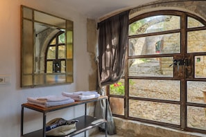 Une pièce dotée d’une grande fenêtre en arc de cercle, d’un miroir, d’un porte-serviettes et d’une petite table.