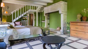 A room with a bed, a table, a dresser, a staircase, and a green wall. - Sur La Calade Guesthouse with Mountain View, Shared Pool and Wi-Fi (Vagnas)