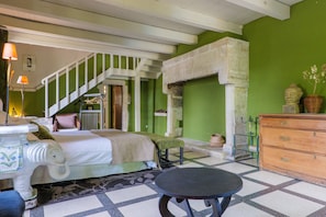 Ein Zimmer mit einem Bett, einem Tisch, einem Schminktisch und einer Wendeltreppe, dessen Wand grün ist.