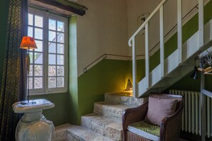A staircase with a handrail, a wicker chair with a cushion, and a window with a lamp. - Sur La Calade Guesthouse with Mountain View, Shared Pool and Wi-Fi (Vagnas)