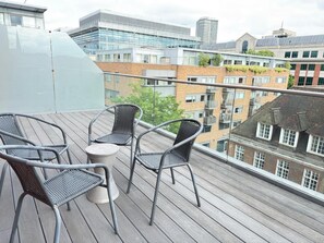 A balcony with wicker chairs and a small table, overlooking a cityscape with modern and traditional buildings. - St James Penthouse - Westminster London (London)