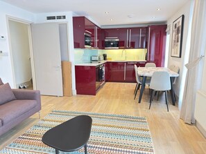 A compact living space with a kitchenette, dining area, and a sofa. - St James Penthouse - Westminster London (London)