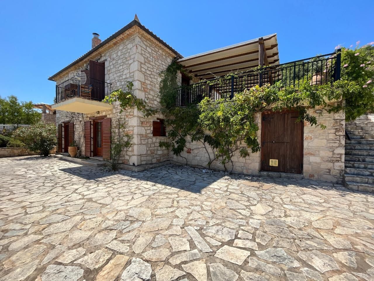 A stone building with a balcony, a stone courtyard, and a wooden door. - Villa Ionis Holiday Villa (Volimes)