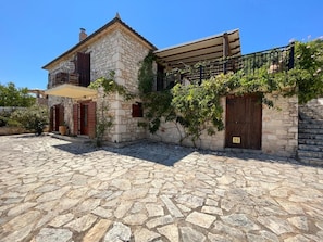 Ein Gebäude aus Stein mit einem Balkon, einem Innenhof aus Stein und einer Holztür.