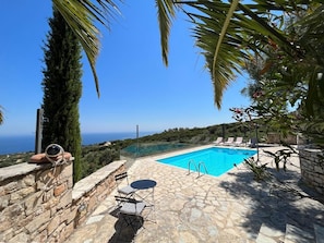 Ein Steingrundbecken mit klarem, blauem Wasser, umgeben von Steinmauern und Palmen, mit Blick auf eine reizvolle Landschaft.