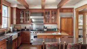 A kitchen with wooden cabinets, a central island, and a dining area with patterned chairs.