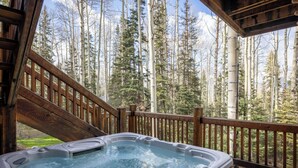 A hot tub on a wooden deck with a forest view.