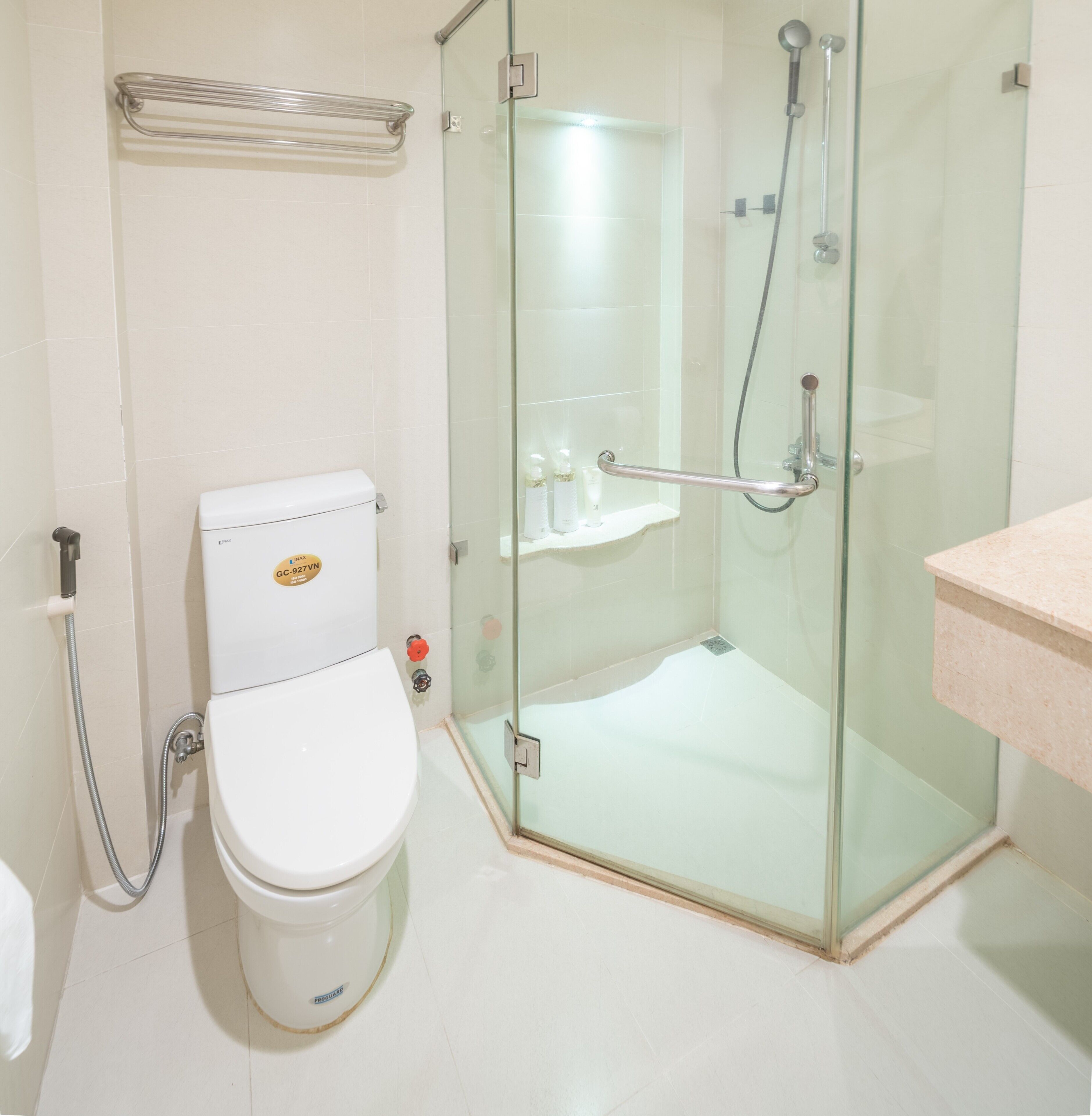 Un baño con inodoro, cabina de ducha de vidrio y lavamanos.
